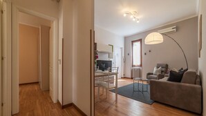 A modern living room with a sofa, a dining table, and a TV. There is a hallway leading to another room. - iFlat | Augustus Suite near Saint Peter (Roma)