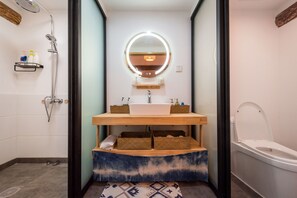 Un baño con un lavabo blanco, un espejo redondo y una ducha.