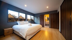 Un dormitorio moderno con una cama grande, suelo de madera y vistas al exterior.