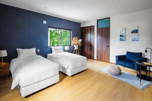 Un dormitorio moderno con dos camas, un sofá azul y un ventanal grande.