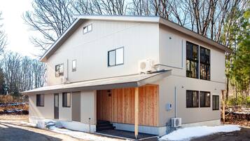 A modern two-story house with a covered garage and a wooden door.