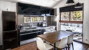 Una cocina moderna con comedor, piso de madera y grandes ventanales con vistas a un paisaje nevado.