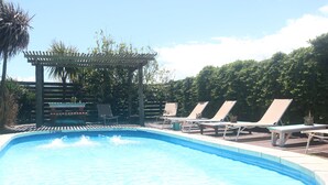 Una piscina con sillas de descanso y una pérgola.