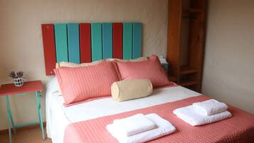 Cozy retreat with a neatly made bed, featuring a patterned bedspread and two pillows, and a small table with a decorative item.