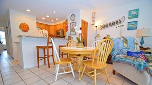 A kitchen with wooden cabinets, a dining table with chairs, a clock on the wall, and a sign for canoe rentals.