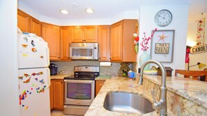 A kitchen with wooden cabinets, stainless steel appliances, a granite countertop, and a sink.