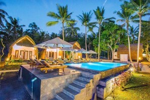 Resort com piscina, espreguiçadeiras e palafitas.