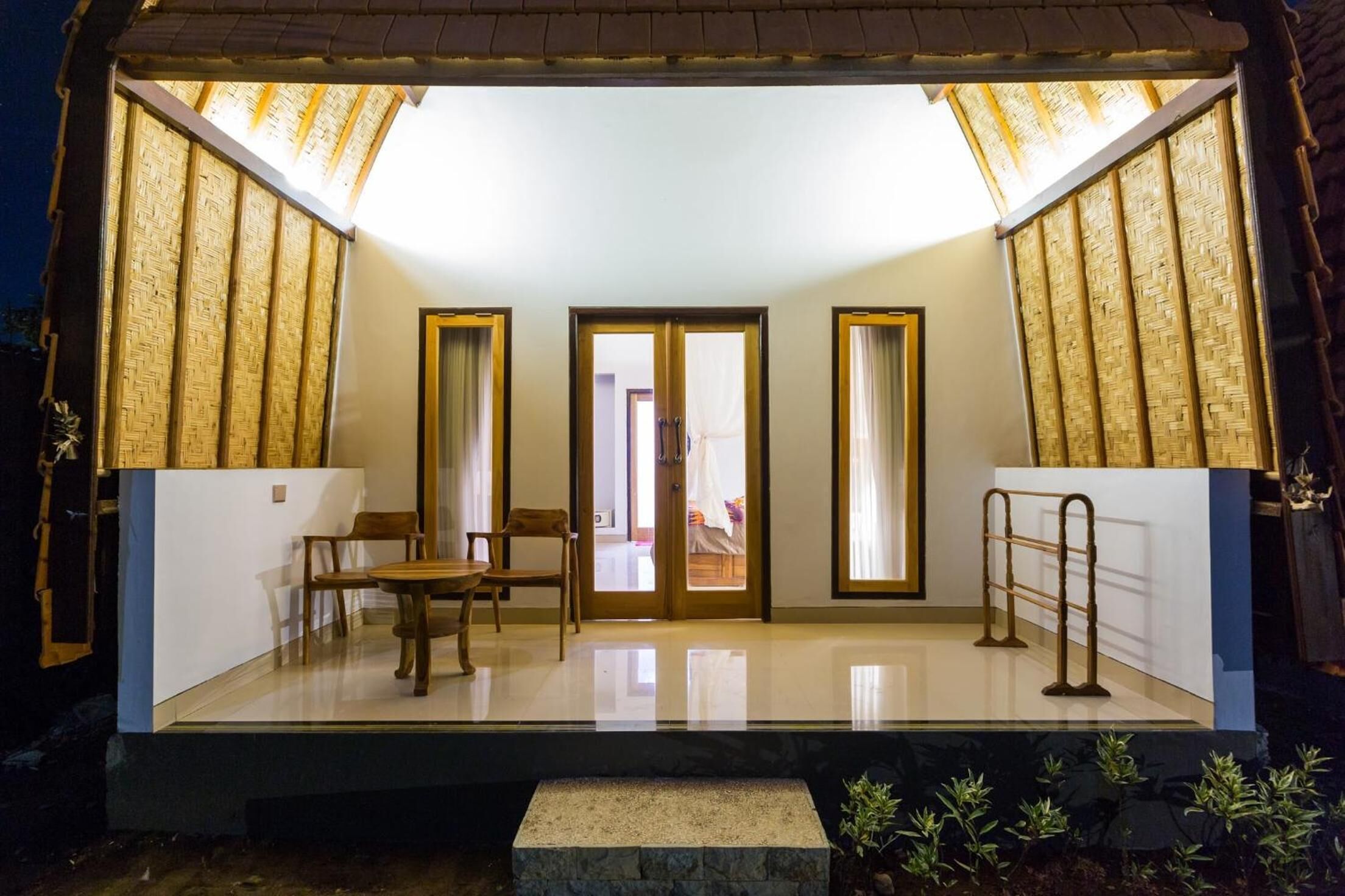 Una habitación moderna y bien iluminada, con un separador de vidrio, muebles de madera y un pequeño banco de piedra.