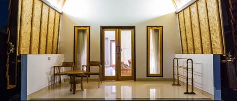Una habitación moderna y bien iluminada, con un separador de vidrio, muebles de madera y un pequeño banco de piedra.