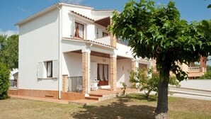 A two-story residential building with a balcony, a small porch, and a tree in the foreground. - Villa with swimming-pool and garden.HUTG-015589 (l'Escala)