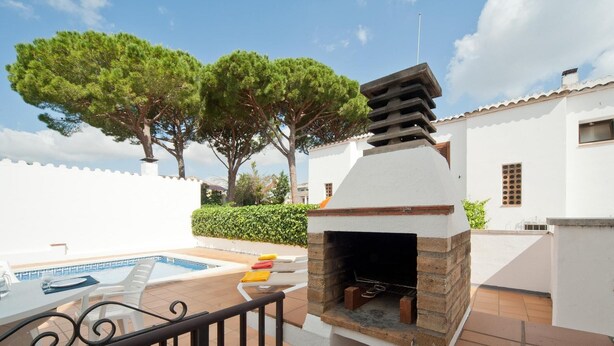 A patio with a barbecue grill, a pool, and a white building with a tiled roof. - Villa with swimming-pool and garden.HUTG-015589 (l'Escala)