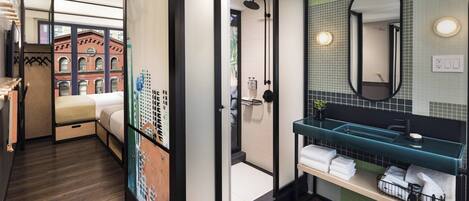 A modern hotel bathroom with a shower, a sink with a green countertop, and a mirror.