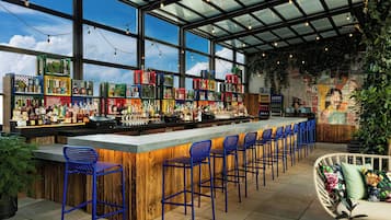 Una zona de bar con una barra larga, taburetes azules y una variedad de botellas y vasos.