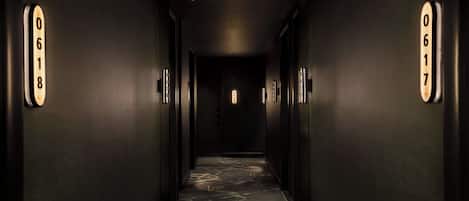 A hallway with dark walls, illuminated numbers on the walls, and a patterned carpet.