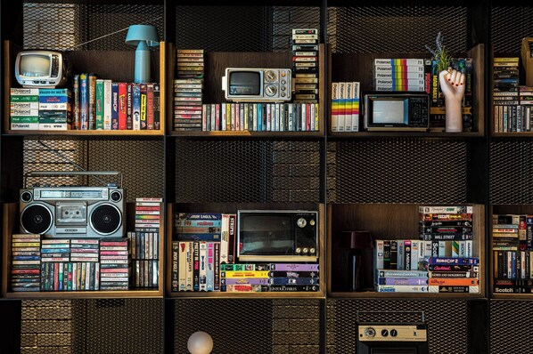 Una estantería con varios libros y aparatos electrónicos antiguos.