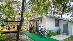 A small, single-story building with a green carpet leading to the entrance, a bicycle parked outside, and a sign indicating a laundry service. - 1BR NEAR WATER + HEART of CR RIVER-Manatees, Golf, Fish, Beach, Food (Crystal River)