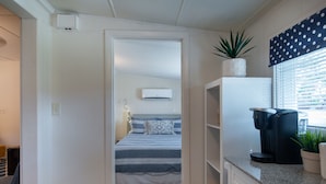 A compact bedroom with a bed, bedside table, and an air conditioning unit. - 1BR NEAR WATER + HEART of CR RIVER-Manatees, Golf, Fish, Beach, Food (Crystal River)