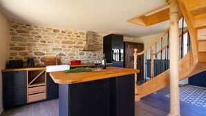 Een keuken met een stenen muur, een houten aanrecht en een houten trap.