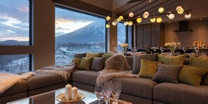 A modern living room with a large window overlooking a snowy landscape and a mountain. - Panorama Niseko (Kutchan)