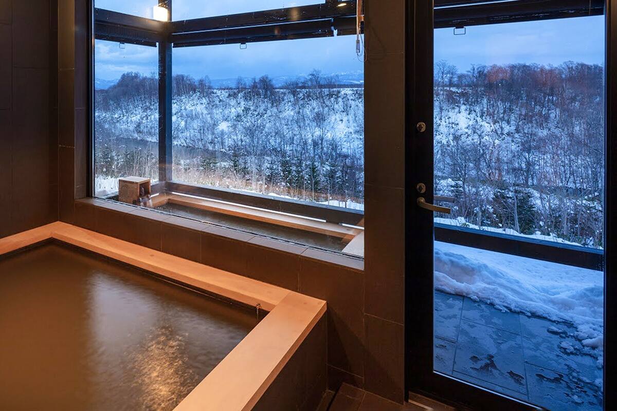 A sauna with a view of a snowy forest.