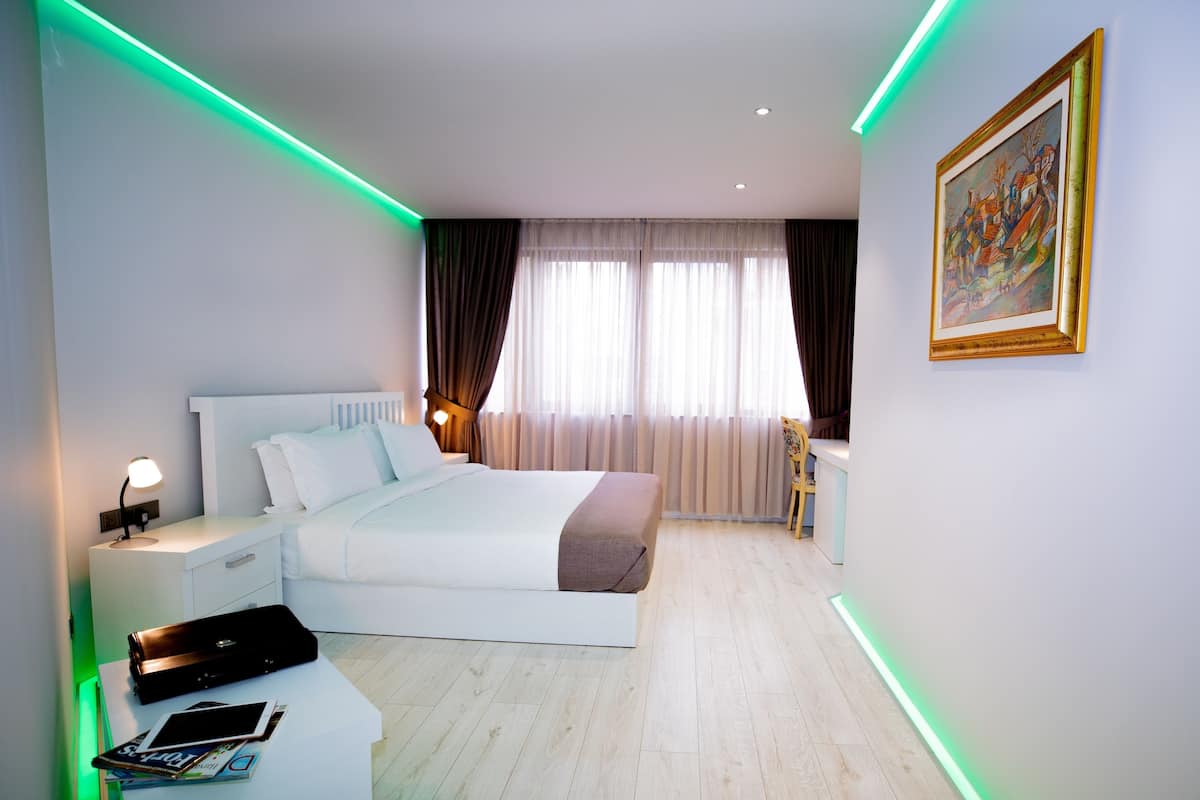 A modern bedroom with a bed, bedside table, lamp, and a painting on the wall.