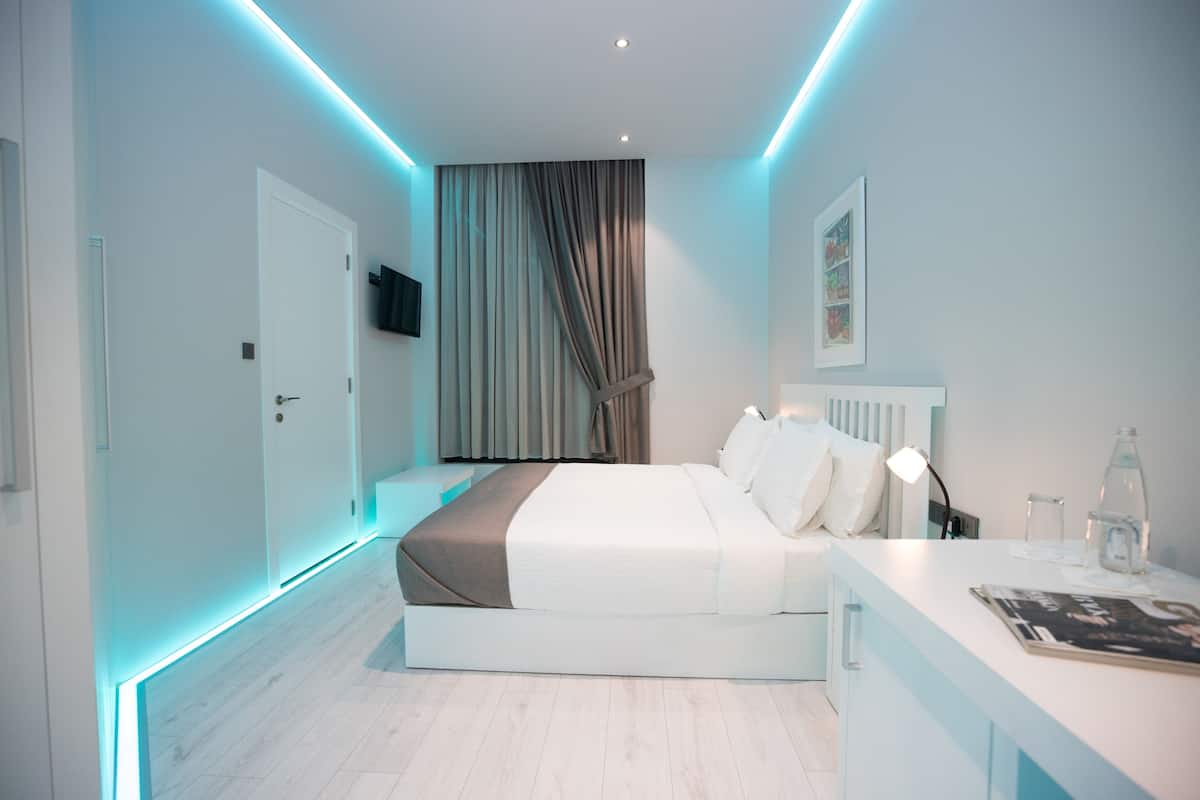 A modern bedroom with a bed, bedside table, and a TV mounted on the wall.