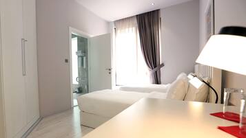 Una habitación de hotel con cama, escritorio, espejo y ventana con cortinas.