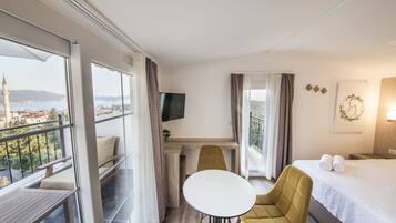 Une chambre d’hôtel avec un balcon, un lit, une télévision, une petite table et un canapé.