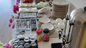 Montaje tipo bufé con diversos alimentos, utensilios y una máquina de café.