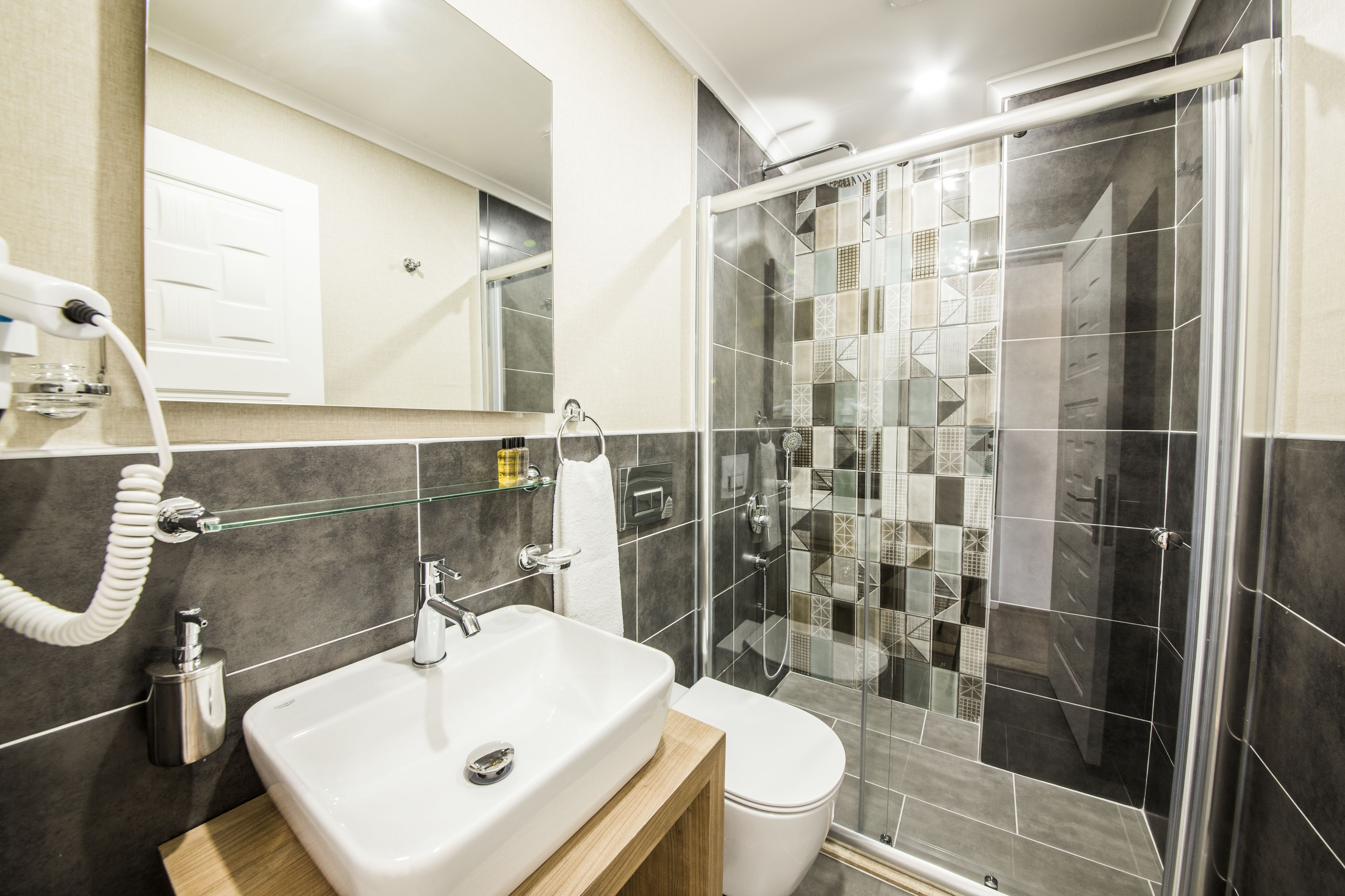 A modern bathroom with a white sink, mirror, and glass-enclosed shower.