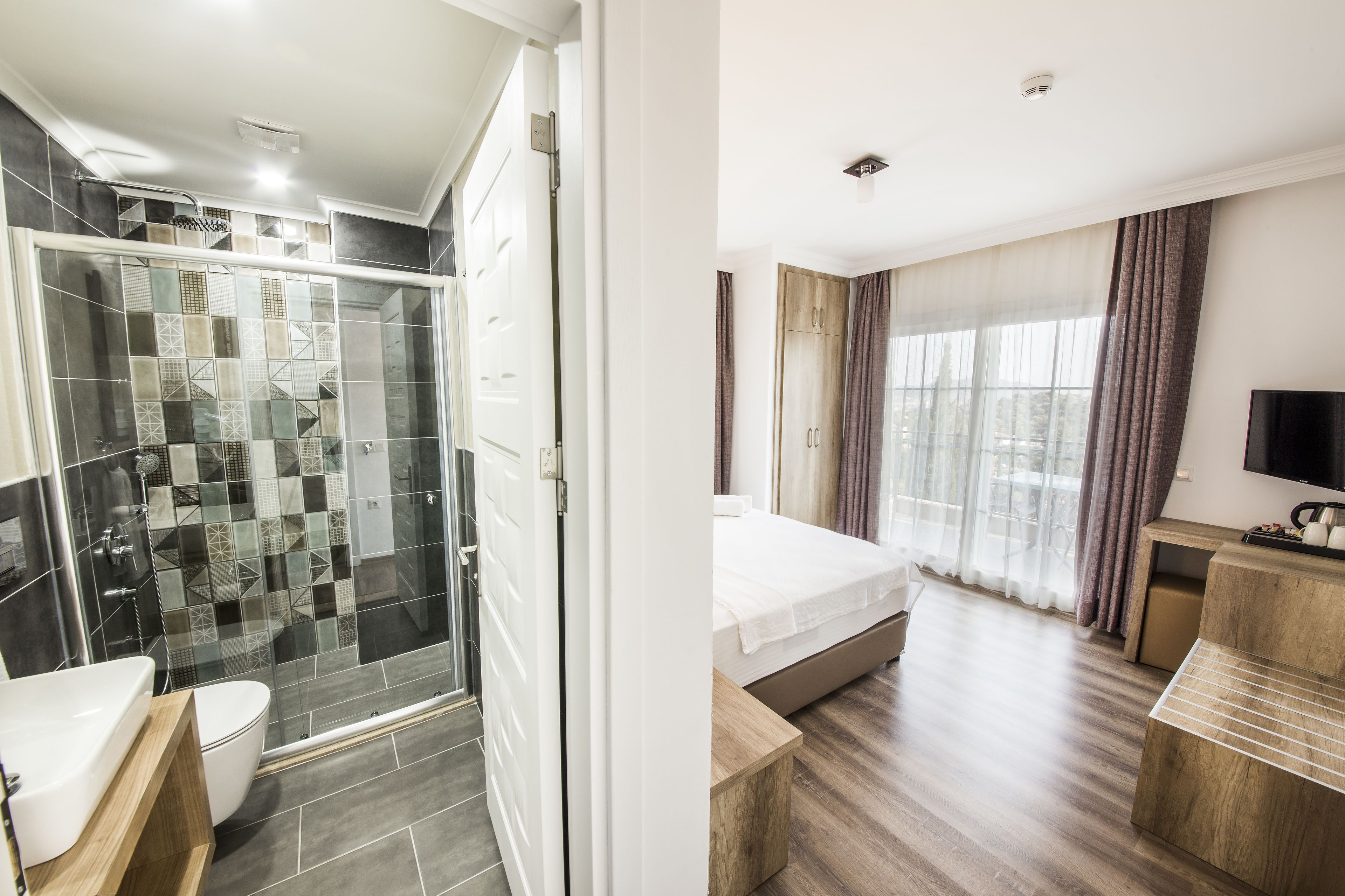 Habitación de hotel moderna con ducha, inodoro y una cama con televisión.