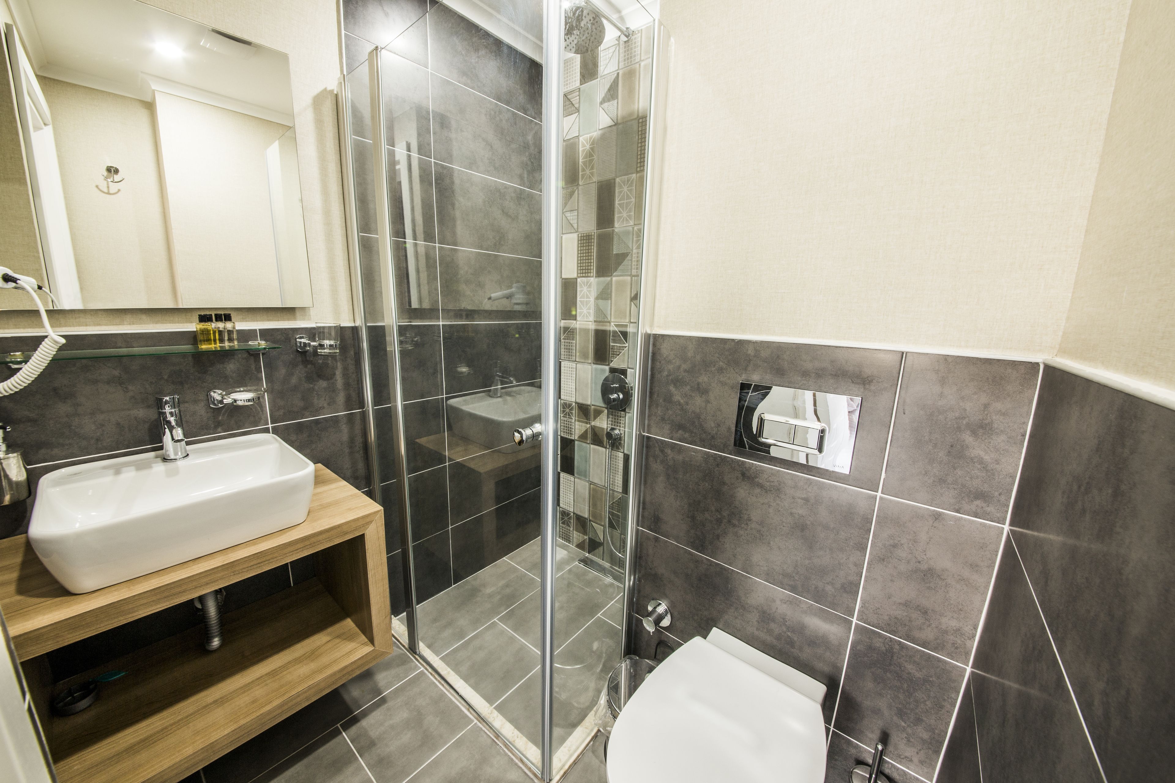 A modern bathroom with a glass-enclosed shower, a wooden vanity with a sink, and a toilet.