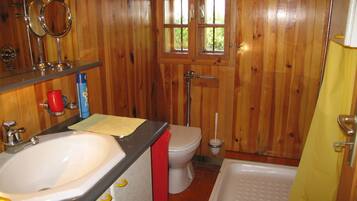 Un baño revestido de paneles de madera con lavamanos, inodoro y bañera.