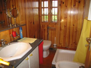 A wooden-paneled bathroom with a sink, toilet, and bathtub.