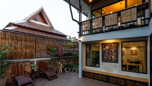 A modern building with a balcony, wooden furniture, and potted plants. - Hostel One Art & Gallery (Chiang Mai)