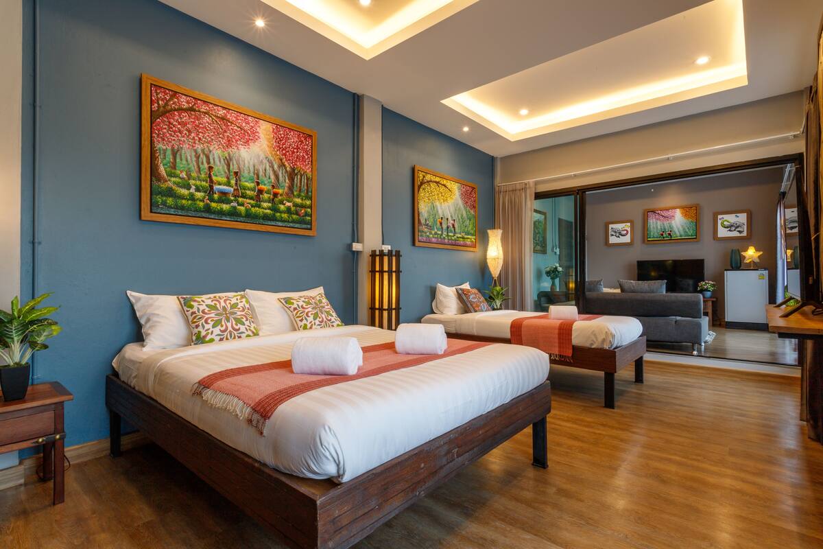 A modern hotel room with a large bed, a sofa, and two paintings on the wall.