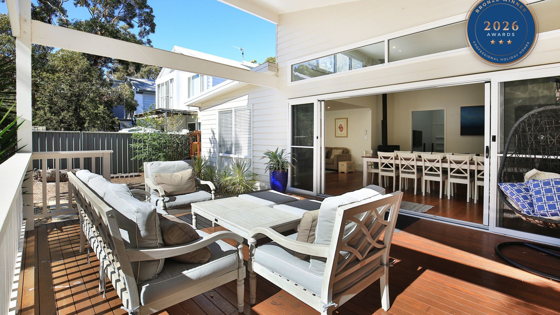 A modern outdoor patio with a dining area, seating, and a view of the house.