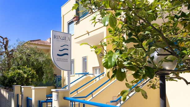 L’entrée d’un hôtel, avec une enseigne indiquant « RIVELA CASAVANZE » et un numéro de téléphone.
