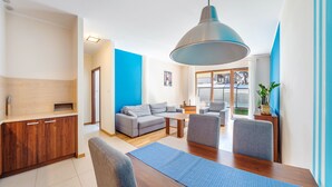A modern living room with a wooden dining table, grey sofas, and a large pendant light. - Apartamenty Sun & Snow Cztery Pory Roku (Wladyslawowo)