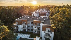 A multi-story building with a flat roof, surrounded by trees. - Apartamenty Sun & Snow Cztery Pory Roku (Wladyslawowo)