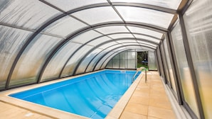 A swimming pool with a glass ceiling, surrounded by a tiled floor. - Apartamenty Sun & Snow Cztery Pory Roku (Wladyslawowo)