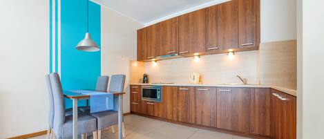 A modern kitchen with wooden cabinets, a built-in oven, and a dining area with a table and chairs.