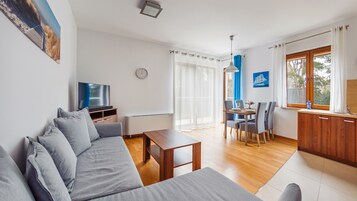 Uma sala de estar moderna com sofá, televisão, mesa de jantar e cadeiras.