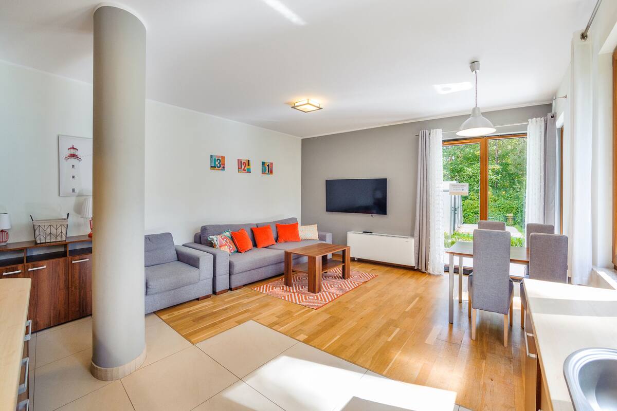 A modern living room with a grey sofa, wooden coffee table, and a TV mounted on the wall.