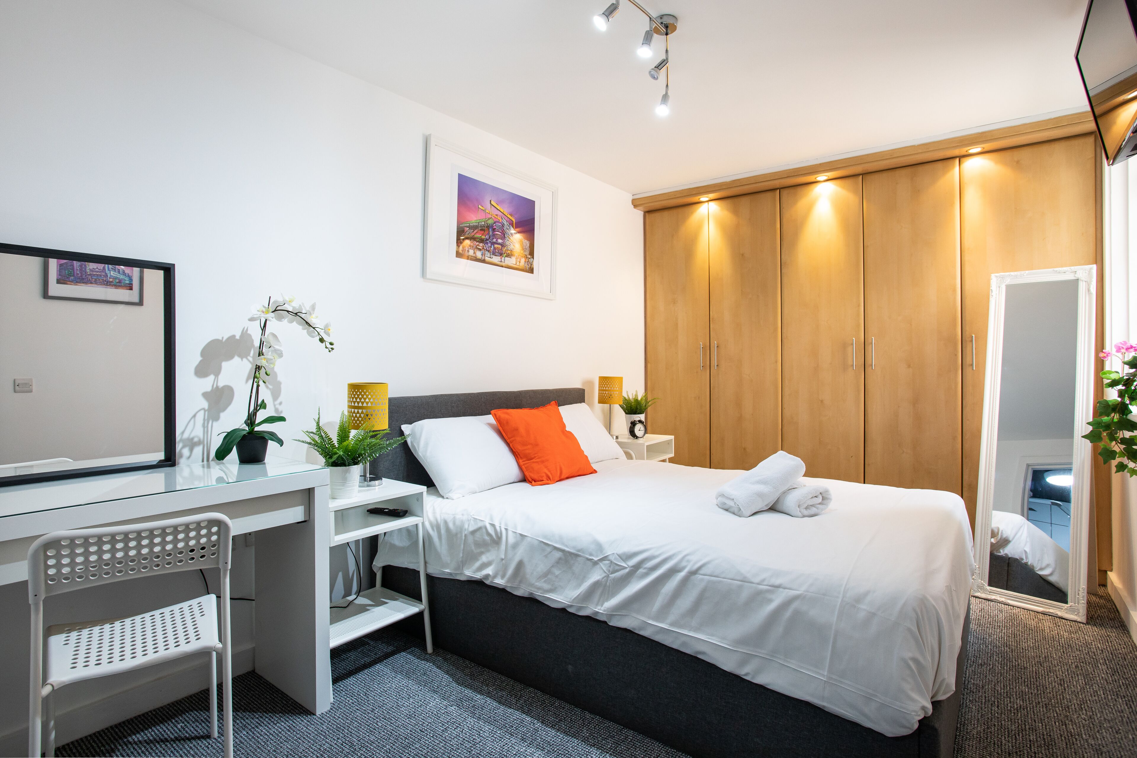 Een moderne slaapkamer met een bed, bureau, stoel en kledingkast.