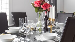 Une table à manger dressée avec des assiettes, des verres et des couverts.
