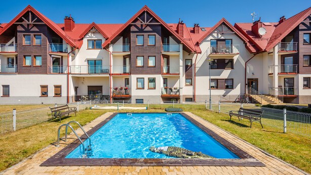 A residential building with a swimming pool, balconies, and a red-tiled roof. - Apartamenty Sun & Snow Lisi Jar (Wladyslawowo)