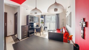 A modern living room with a dining area, a kitchen, and a TV in the background. - Apartamenty Sun & Snow Lisi Jar (Wladyslawowo)