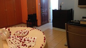 A hotel room with a bed covered in rose petals, a wooden wardrobe, a small table with a chair, and a fireplace. - Chester View Homestay - Hostel (Mlolongo)