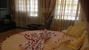 A bed with rose petals and a towel arranged on it, a chair, and a television in the room. - Chester View Homestay - Hostel (Mlolongo)